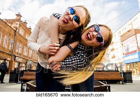Stock Image - Women making faces in city. Fotosearch