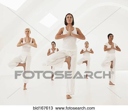 Stock Image - Women practicing yoga in class. Fotosearch