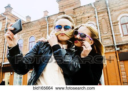 Picture - Women taking selfie in city. Fotosearch