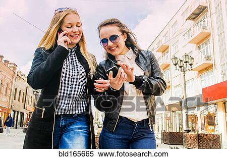 Stock Photography - Women using cell phones in city. Fotosearch