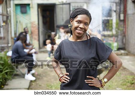 Stock Image - African American woman standing in backyard. Fotosearch