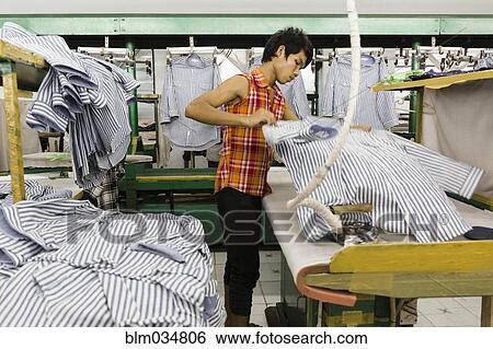 Stock Photograph - Asian worker ironing shirt in garment factory. Fotosearch
