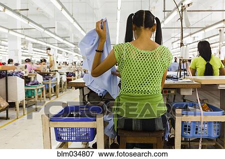 Stock Photo - Asian worker sewing clothing in garment factory. Fotosearch