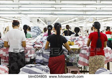 Stock Photography - Asian workers sewing clothing in garment factory. Fotosearch