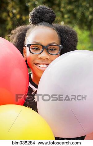 Picture - Black girl holding bunch of balloons. Fotosearch