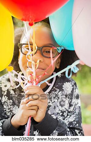 Stock Photography - Black girl holding bunch of balloons. Fotosearch