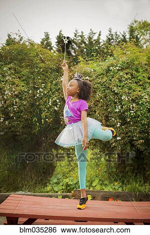 Stock Photograph - Black girl playing ballerina on picnic table. Fotosearch