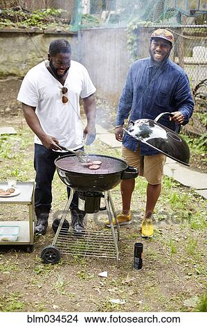 Black men grilling hamburgers at backyard barbecue View Large Photo Image Picture - Black men grilling hamburgers at backyard barbecue. Fotosearch