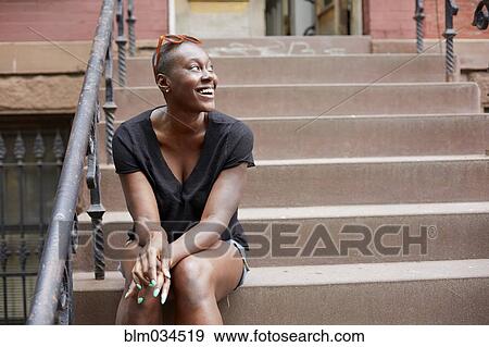 Stock Photo - Black woman sitting on urban front stoop. Fotosearch