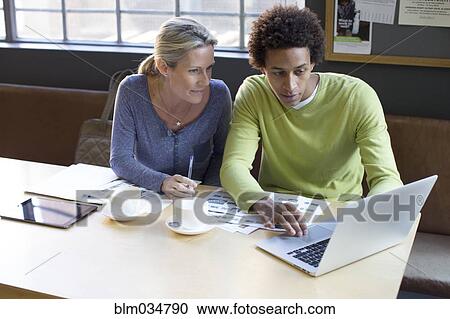 Stock Image - Business people using laptop in office meeting. Fotosearch