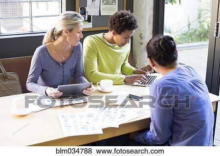 Stock Photo - Business people using technology in office meeting. Fotosearch