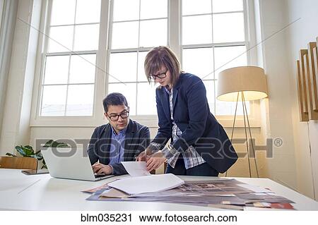 Stock Image - Business people working at desk in office. Fotosearch