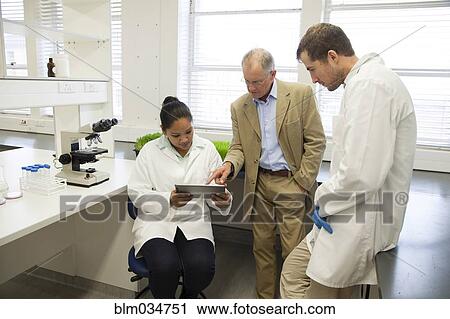 Stock Image - Businessman and scientists using digital tablet in laboratory. Fotosearch