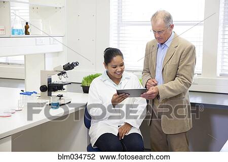 Stock Image - Businessman and scientists using digital tablet in laboratory. Fotosearch