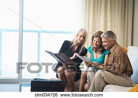 Businesswoman talking to couple on sofa View Large Photo Image Stock Photograph - Businesswoman talking to couple on sofa. Fotosearch