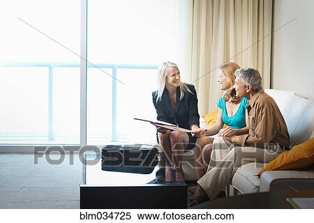 Businesswoman talking to couple on sofa View Large Photo Image Stock Photography - Businesswoman talking to couple on sofa. Fotosearch