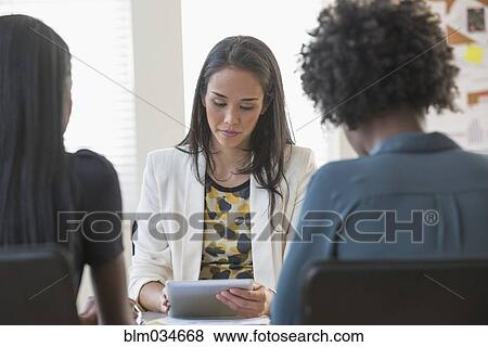 Businesswoman using digital tablet in office meeting View Large Photo Image Stock Photo - Businesswoman using digital tablet in office meeting. Fotosearch