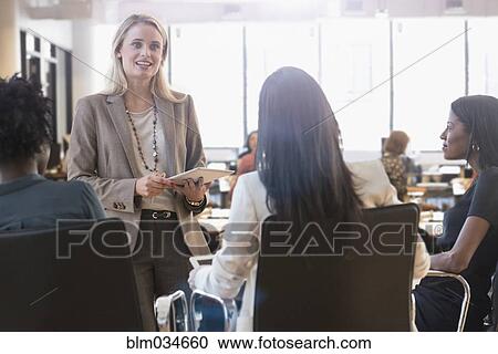 Stock Image - Businesswomen talking in office meeting. Fotosearch