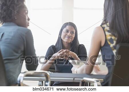 Stock Image - Businesswomen talking in office meeting. Fotosearch