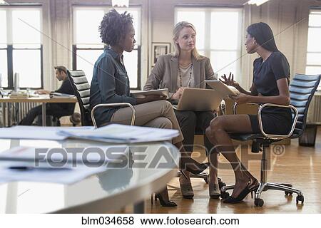 Stock Photo - Businesswomen talking in office meeting. Fotosearch