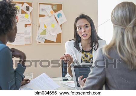 Stock Photograph - Businesswomen talking in office meeting. Fotosearch