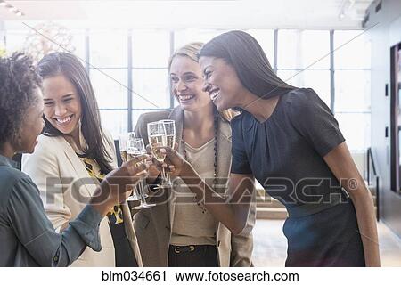 Stock Image - Businesswomen toasting with champagne in office. Fotosearch