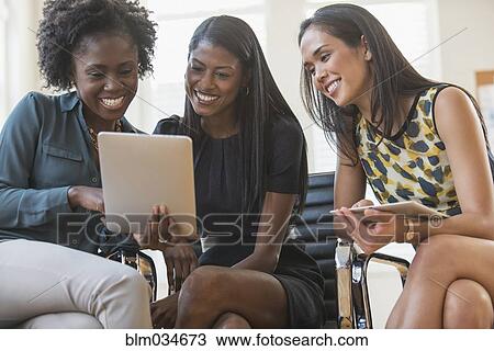 Stock Image - Businesswomen using digital tablet in office. Fotosearch