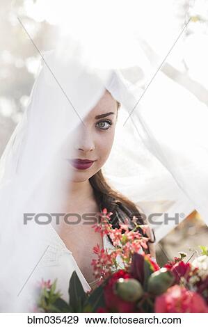 Stock Photo - Caucasian bride holding bouquet under veil. Fotosearch