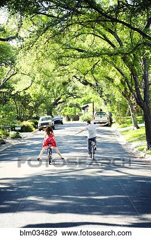 Stock Photo - Caucasian children riding bicycles on suburban neighborhood street. Fotosearch