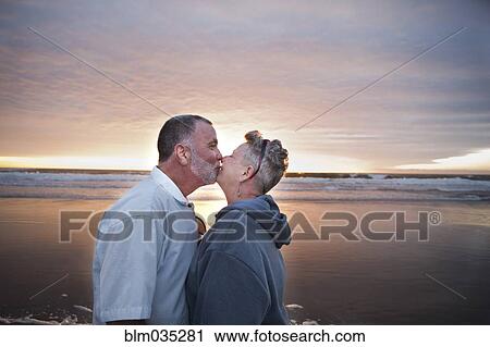 Caucasian couple kissing on beach at sunset View Large Photo Image Stock Image - Caucasian couple kissing on beach at sunset. Fotosearch