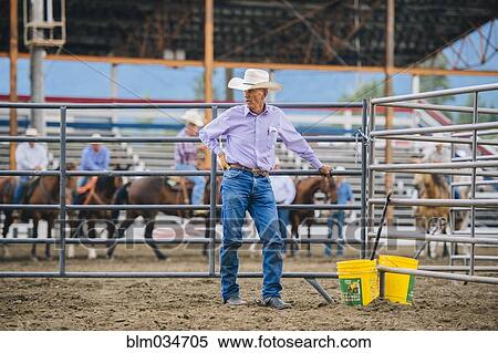 Stock Photography - Caucasian cowboy standing at rodeo fence. Fotosearch