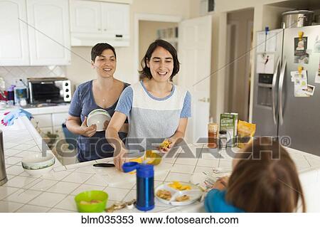 Stock Image - Caucasian family eating breakfast in kitchen. Fotosearch