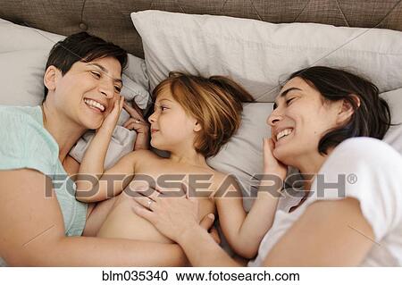 Stock Image - Caucasian family playing in bed. Fotosearch