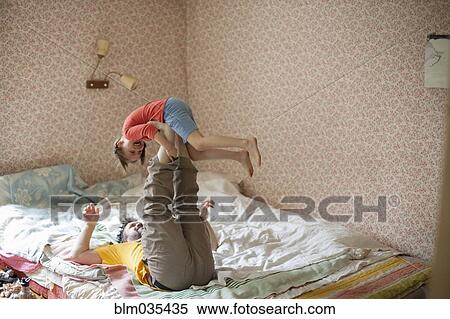 Stock Photography - Caucasian father and daughter playing on bed. Fotosearch