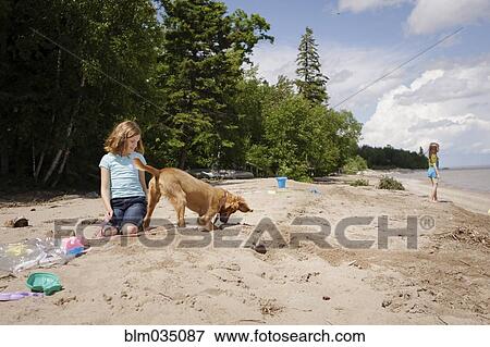 Stock Photo - Caucasian girl and puppy playing on beach. Fotosearch