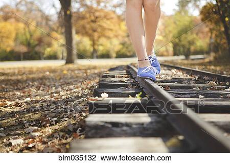 Stock Image - Caucasian girl balancing on train tracks. Fotosearch