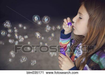 Stock Image - Caucasian girl blowing bubbles. Fotosearch