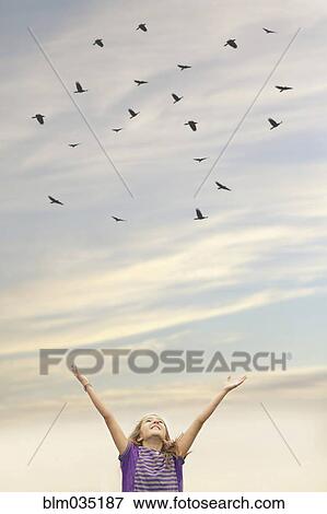 Stock Photo - Caucasian girl cheering under flock of birds. Fotosearch