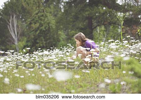 Caucasian girl crouching in field of flowers View Large Photo Image Stock Photograph - Caucasian girl crouching in field of flowers. Fotosearch