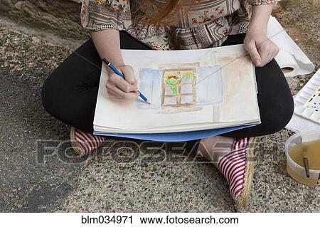 Stock Image - Caucasian girl drawing on concrete ground. Fotosearch