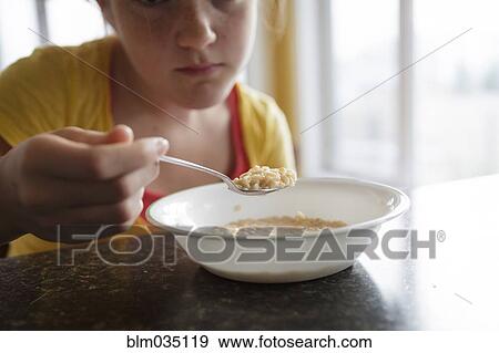 Stock Photo - Caucasian girl eating breakfast at table. Fotosearch
