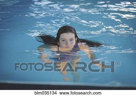 Picture - Caucasian girl floating in swimming pool. Fotosearch