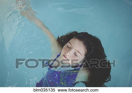 Stock Photography - Caucasian girl floating in swimming pool. Fotosearch