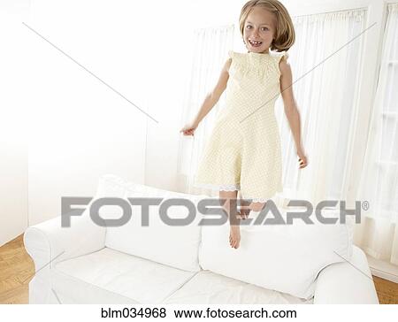 Caucasian girl jumping on sofa in living room View Large Photo Image Stock Photo - Caucasian girl jumping on sofa in living room. Fotosearch