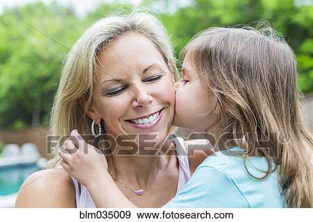 Stock Photo - Caucasian girl kissing mother in backyard. Fotosearch