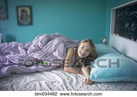 Stock Image - Caucasian girl laying on bed. Fotosearch