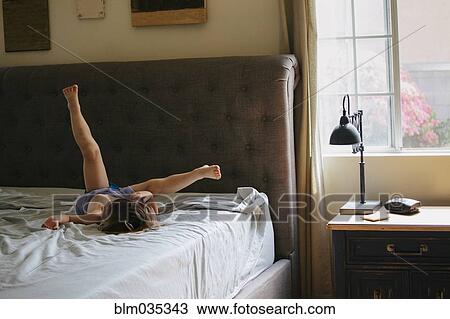 Stock Image - Caucasian girl playing on bed. Fotosearch