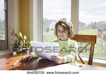 Picture - Caucasian girl reading papers at table. Fotosearch