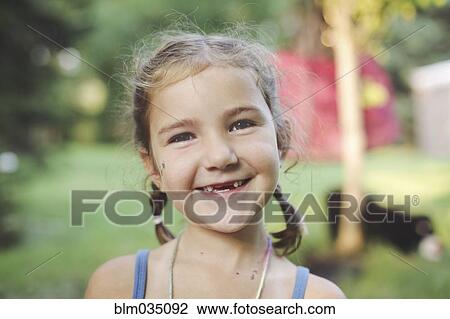 Stock Image - Caucasian girl smiling in backyard. Fotosearch