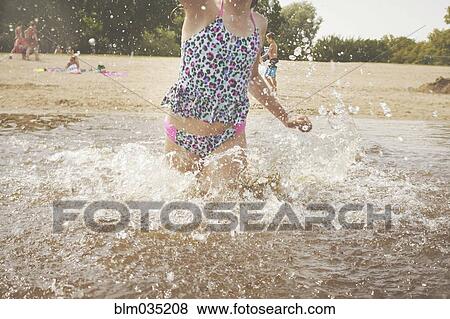 Caucasian girl splashing in waves on beach View Large Photo Image Stock Photo - Caucasian girl splashing in waves on beach. Fotosearch